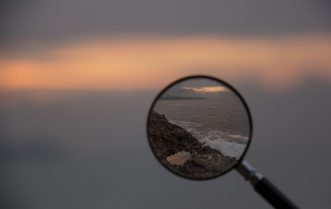 a maginifying glass showing a clear frame of an otherwise blurry image of coastline